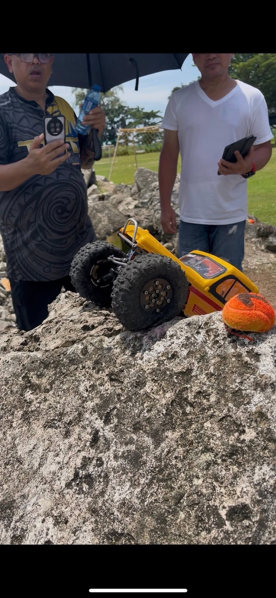 Two hobbyists watching RC crawler summit a boulder at AYRC Talisay