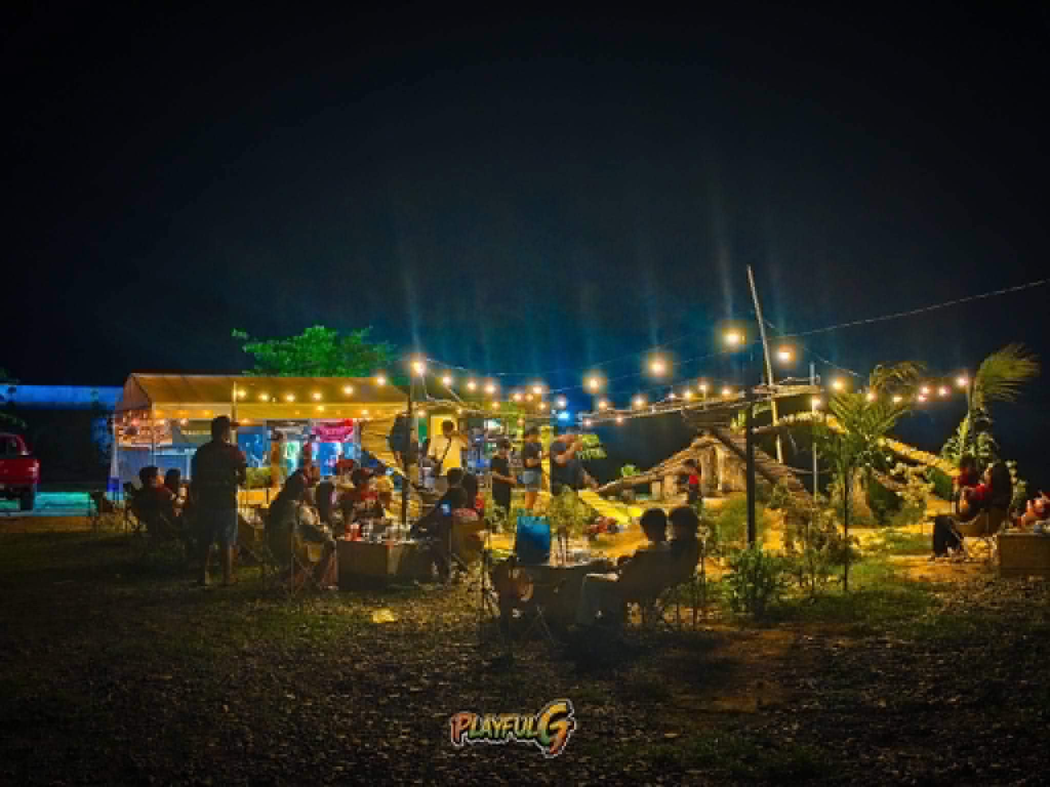 Night scene at Mudace RC Park cafe area with string lights and crowd