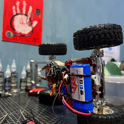 Raven Rigworks workshop close-up showing shock oil bottles, Tamiya paints, and RC crawler parts on a blue-walled workbench in Baliuag Bulacan